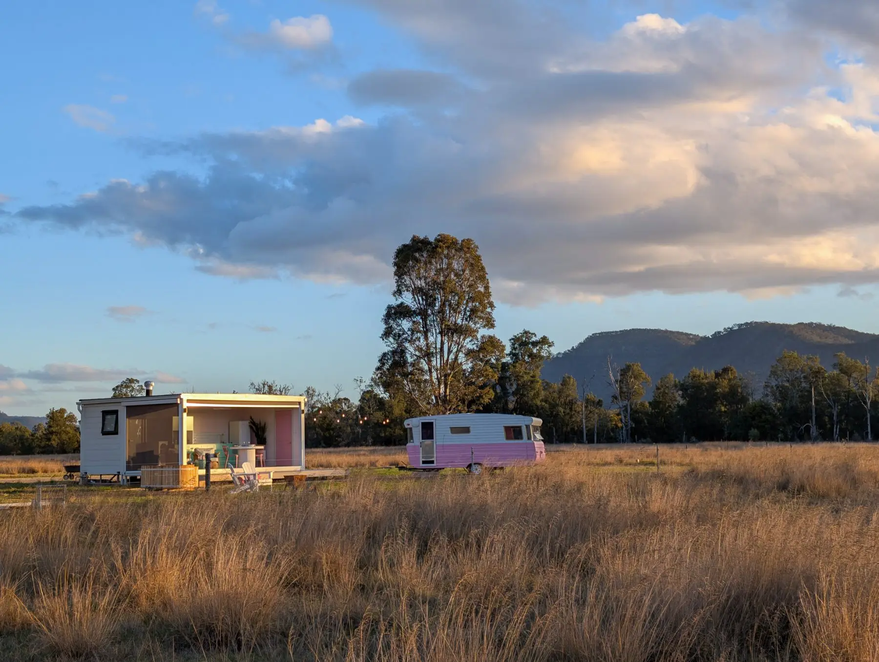 The pavilion and caravan set alone in the grass paddock, ranges behind