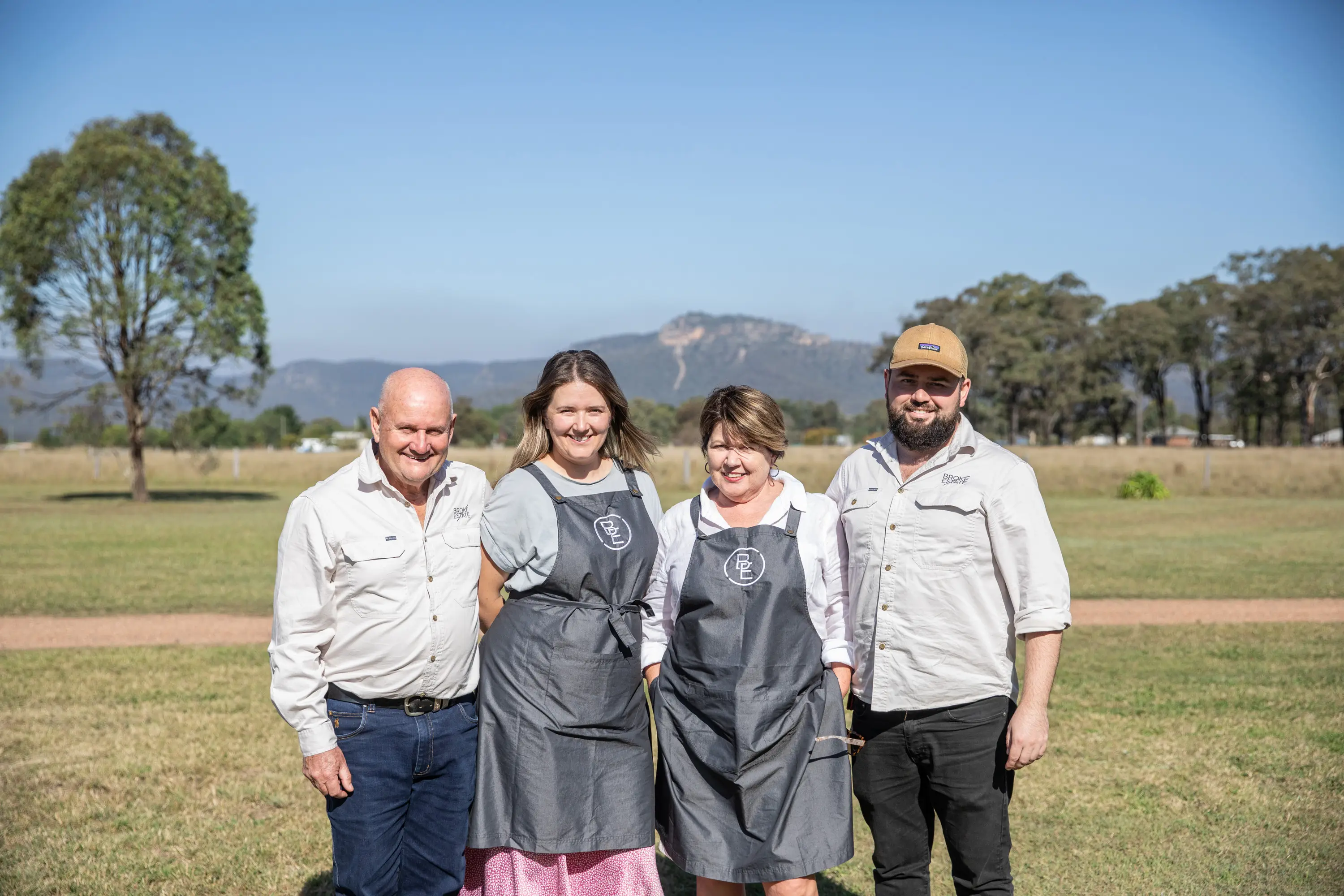 The Tolson family standing together in a paddock at Broke Estate, with the Brokenback Range behind