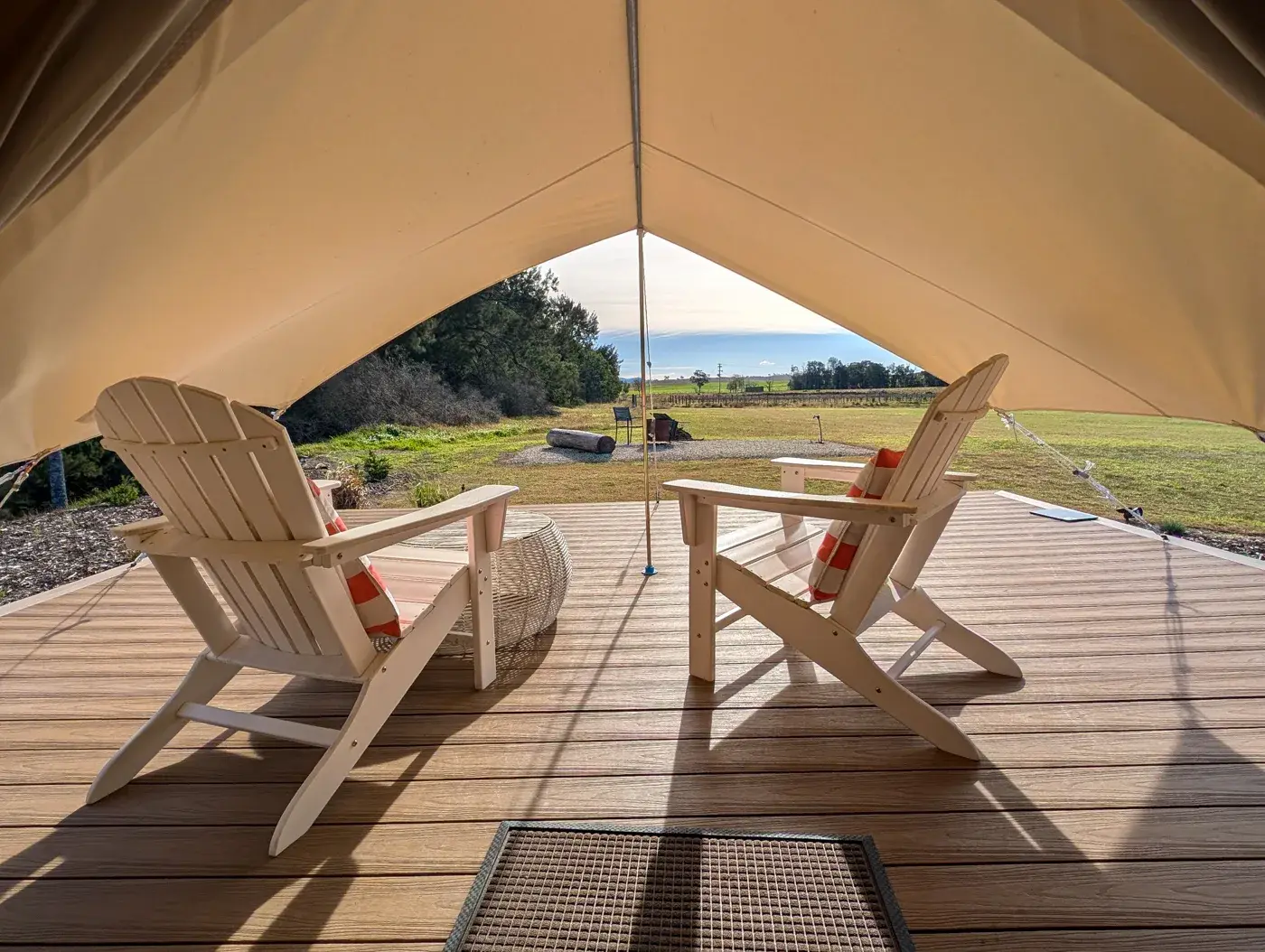 Two chairs under the tent awning looking out to the firepit and the paddock beyond