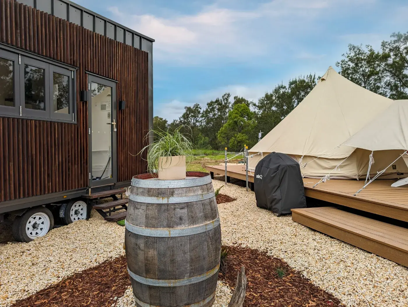 The pod and the tent from the gravel, wine barrel and planting in front