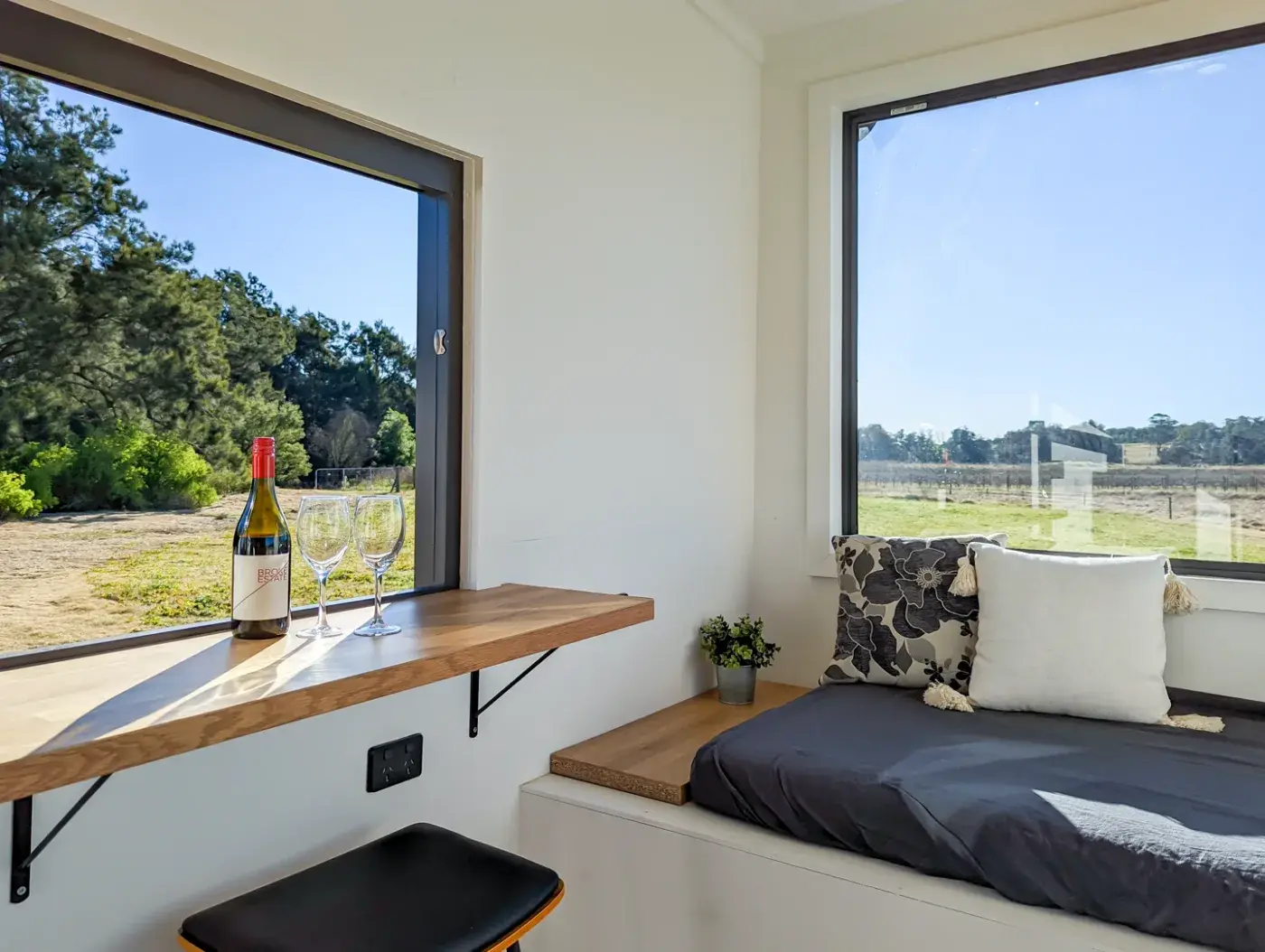 The window seat in the pod with a bottle and glasses on the bench